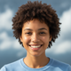 Smiling young adult woman with short curly dark hair, looking at the viewer, conveying satisfaction and trust.